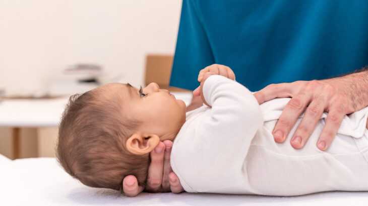 mãos de médico examinando um bebê na maca