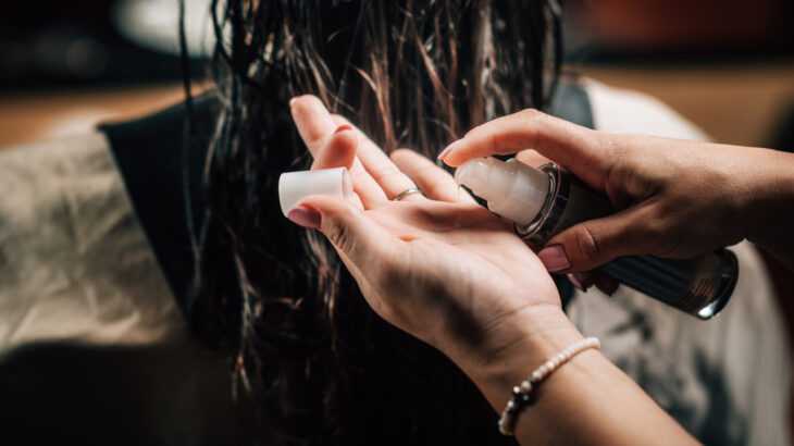 mãos de mulher aplicando óleo no cabelo