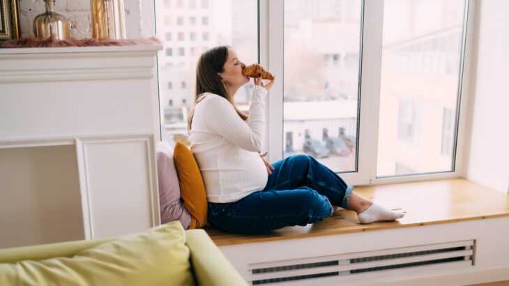 mulher na janela comendo um croassaint