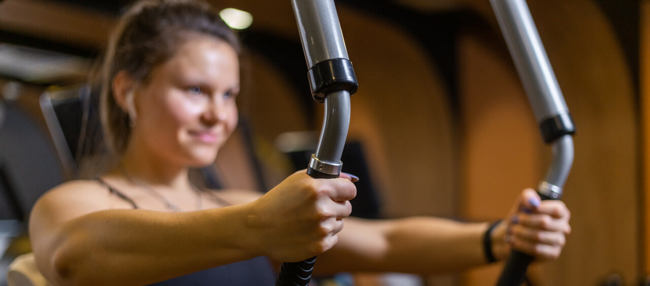 mulher fazendo o exercício peck deck na academia