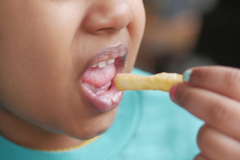 criança com sobrepeso comendo uma batata frita