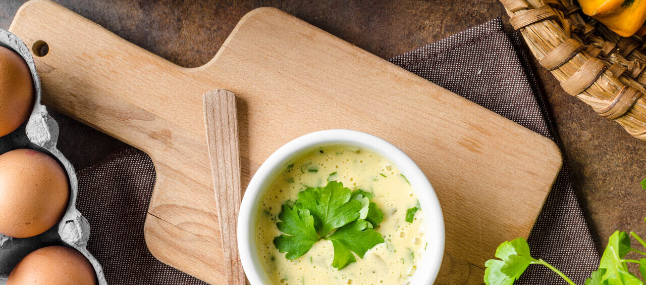 pote de maionese com ervas visto de cima ao lado de ingredientes como ovos e coentro