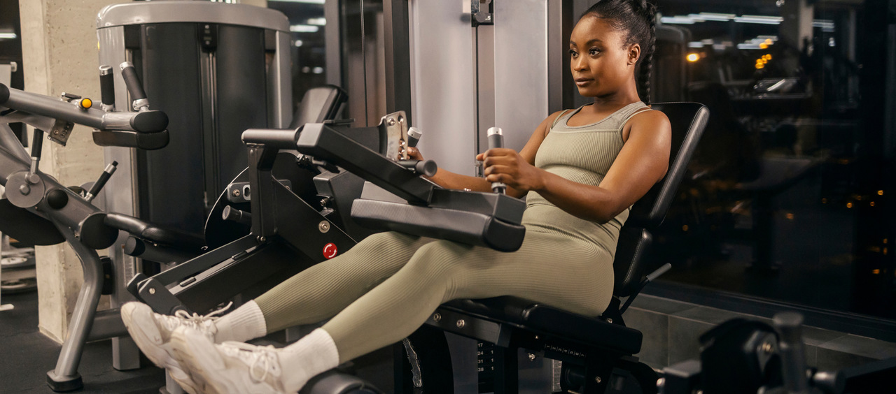 mulher fazendo exercício na cadeira flexora da academia