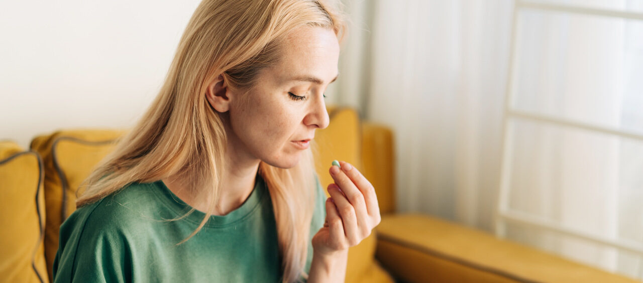mulher tomando um comprimido na sala de casa