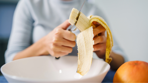 mulher com diverticulite cortando banana.