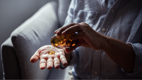 homem idoso colocando pilulas de vitamina A na mão